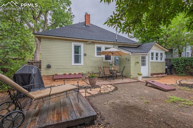 rear view of house featuring a patio area, a chimney, roof with shingles, and fence