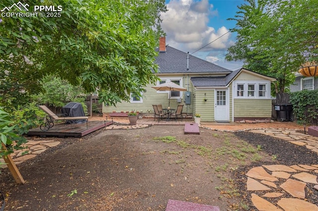 rear view of property with a patio, fence, a wooden deck, a shingled roof, and a chimney