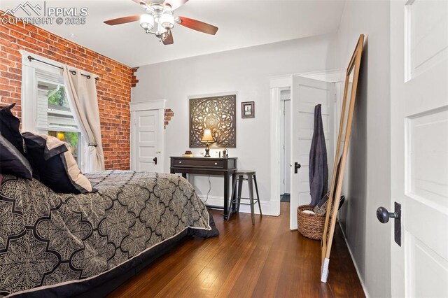 bedroom with ceiling fan, baseboards, brick wall, and dark wood-style flooring