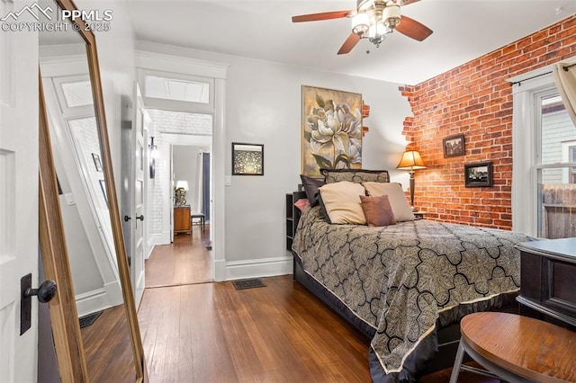 bedroom with brick wall, baseboards, wood-type flooring, and ceiling fan
