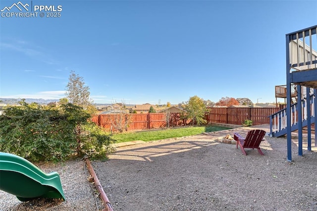 view of yard featuring a fenced backyard, stairway, and a playground