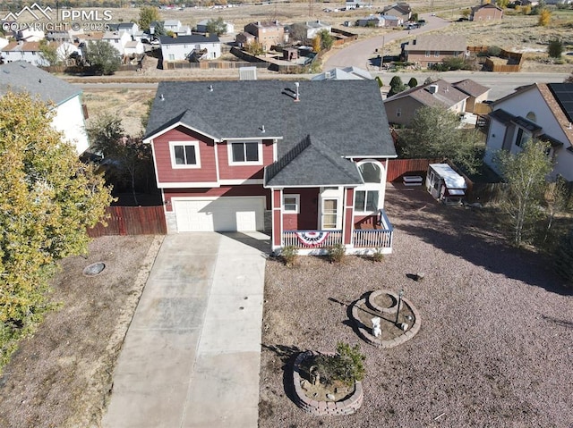 view of front of home featuring a porch, an attached garage, fence, a residential view, and driveway