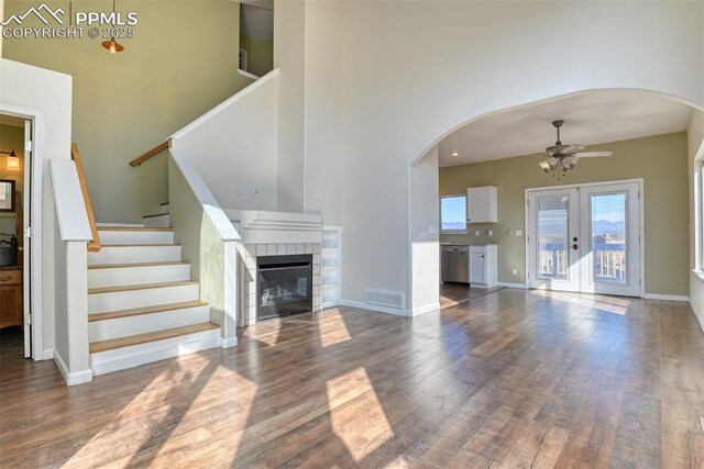 unfurnished living room with baseboards, visible vents, a ceiling fan, wood finished floors, and stairs