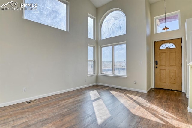 entrance foyer with high vaulted ceiling, visible vents, baseboards, and wood finished floors