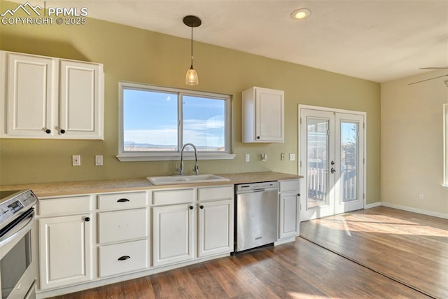 kitchen featuring dark wood-type flooring, stainless steel appliances, light countertops, white cabinetry, and a sink