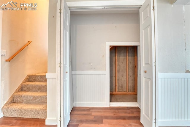 stairway featuring a wainscoted wall and wood finished floors