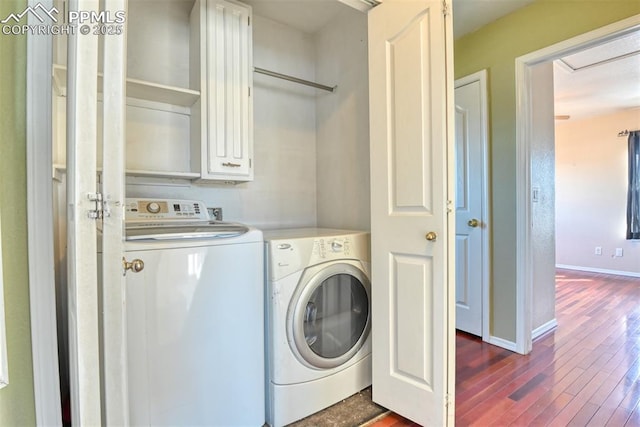 clothes washing area featuring dark wood-style floors, washing machine and dryer, baseboards, and cabinet space