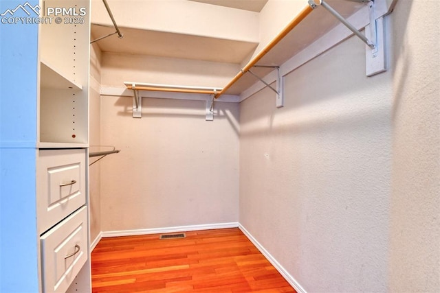 spacious closet with light wood-style floors and visible vents