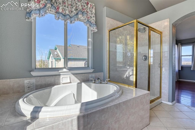 bathroom with a stall shower, tile patterned flooring, and a bath