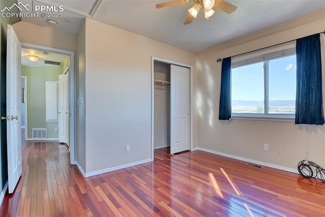 unfurnished bedroom featuring a closet, wood-type flooring, visible vents, and baseboards