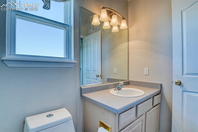 bathroom featuring a textured wall, vanity, and toilet