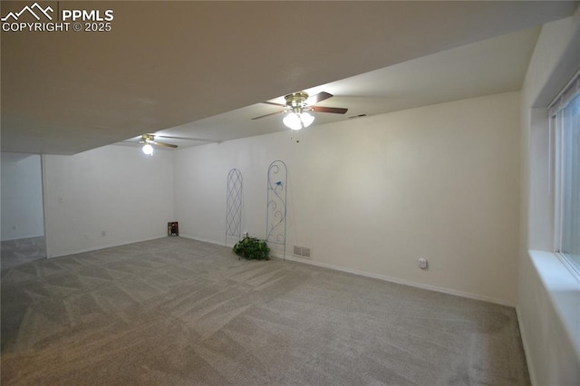 carpeted spare room featuring visible vents and a ceiling fan