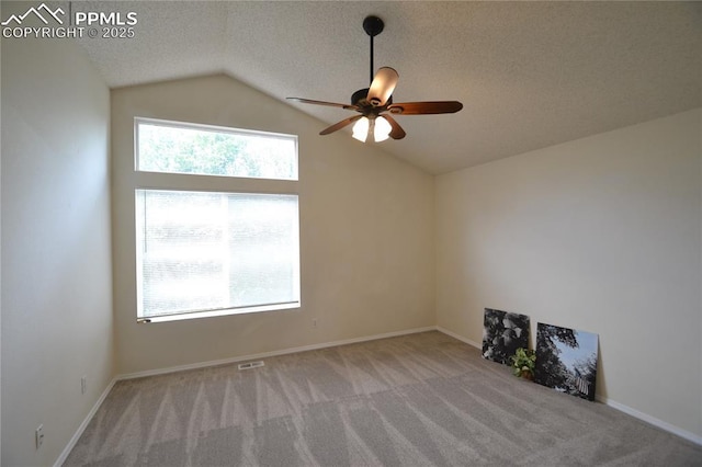 unfurnished room featuring visible vents, ceiling fan, vaulted ceiling, a textured ceiling, and carpet floors