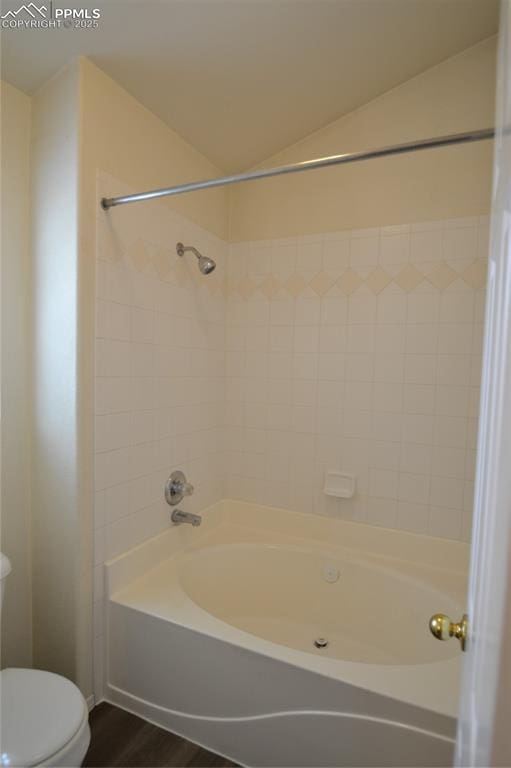 bathroom with vaulted ceiling, wood finished floors, bathtub / shower combination, and toilet