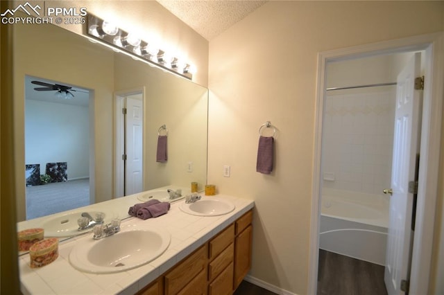 full bathroom with a textured ceiling, double vanity, vaulted ceiling, and a sink