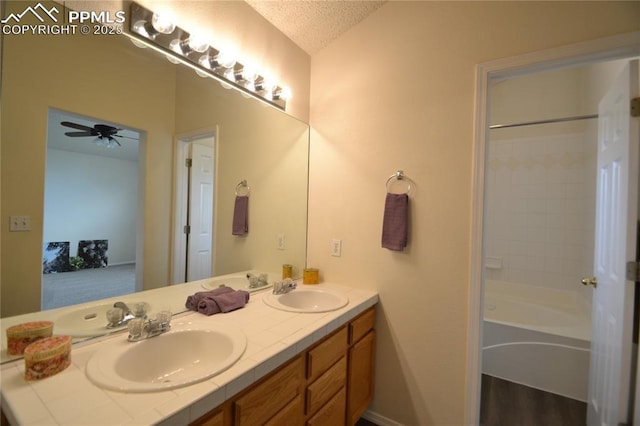 full bathroom with double vanity, a textured ceiling, a sink, and lofted ceiling