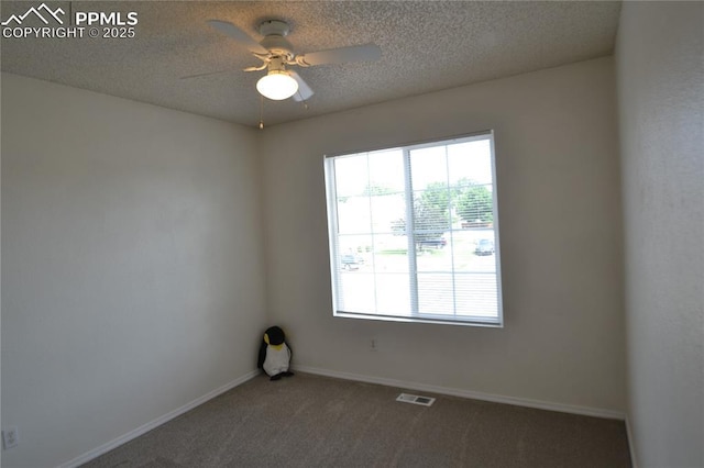 empty room featuring a textured ceiling, carpet floors, a ceiling fan, visible vents, and baseboards