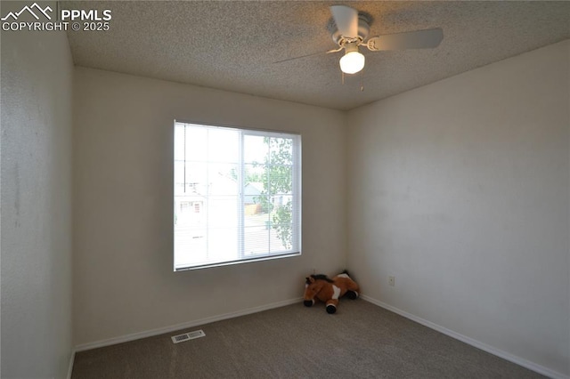 carpeted spare room with a ceiling fan, baseboards, visible vents, and a textured ceiling