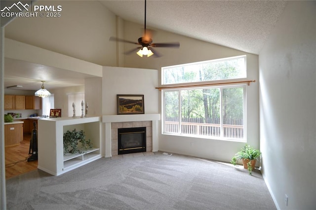 unfurnished living room featuring light carpet, a ceiling fan, a textured ceiling, a fireplace, and high vaulted ceiling