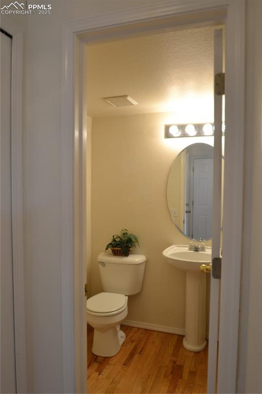 bathroom with a sink, wood finished floors, toilet, and baseboards