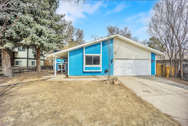 mid-century modern home featuring a garage, concrete driveway, and fence