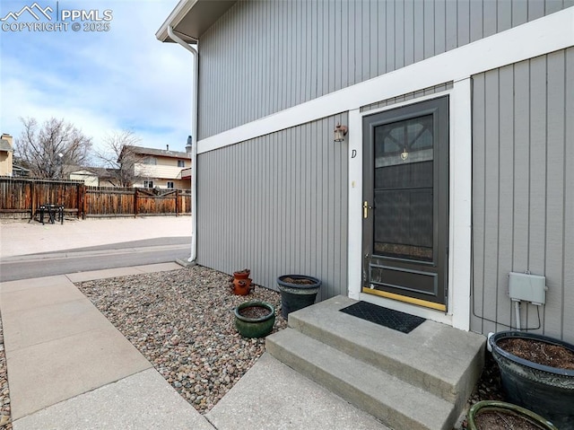 view of exterior entry with fence and a patio