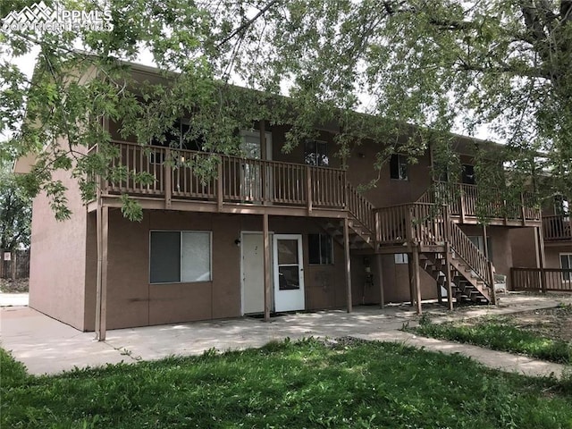 back of property featuring stairs, a patio, and stucco siding