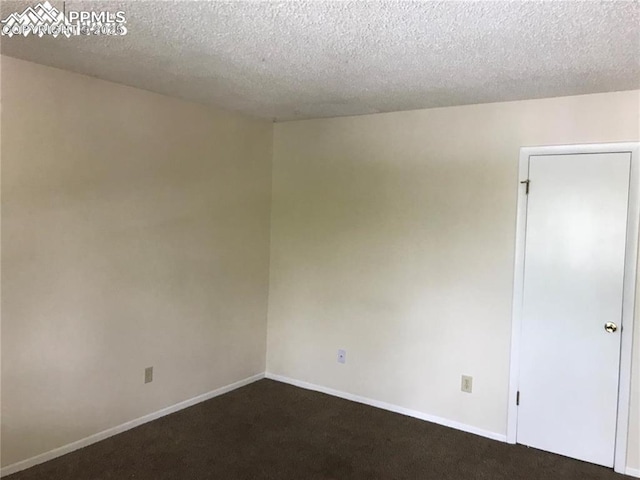 empty room with dark carpet, a textured ceiling, and baseboards