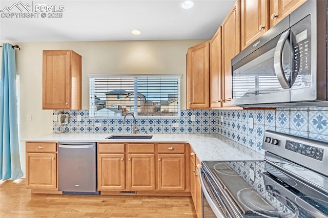 kitchen featuring appliances with stainless steel finishes, light wood-type flooring, light countertops, and a sink