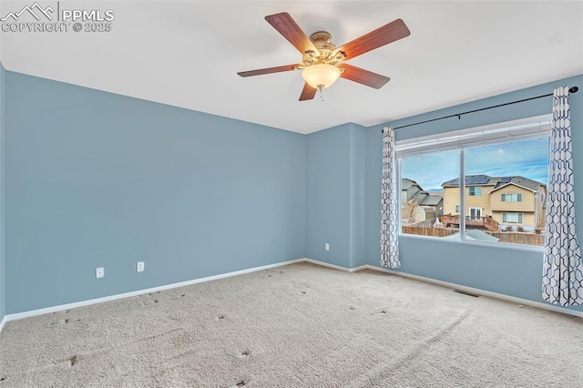 carpeted empty room featuring a ceiling fan, visible vents, and baseboards