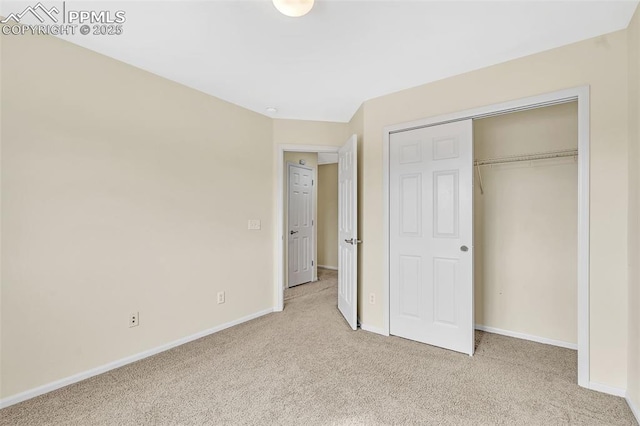 unfurnished bedroom with a closet, light carpet, and baseboards