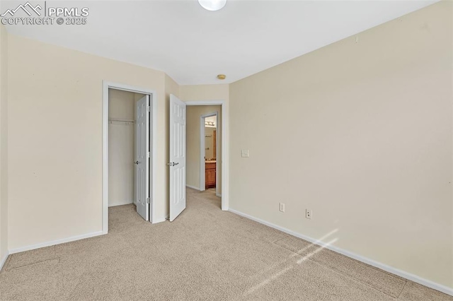 unfurnished bedroom featuring light carpet, a spacious closet, baseboards, and a closet