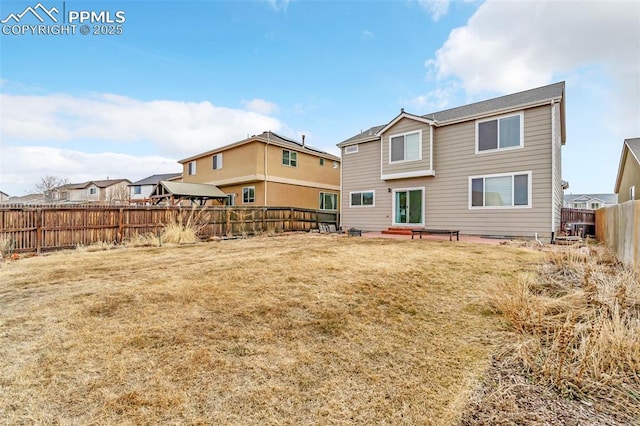 rear view of house with a fenced backyard and a yard