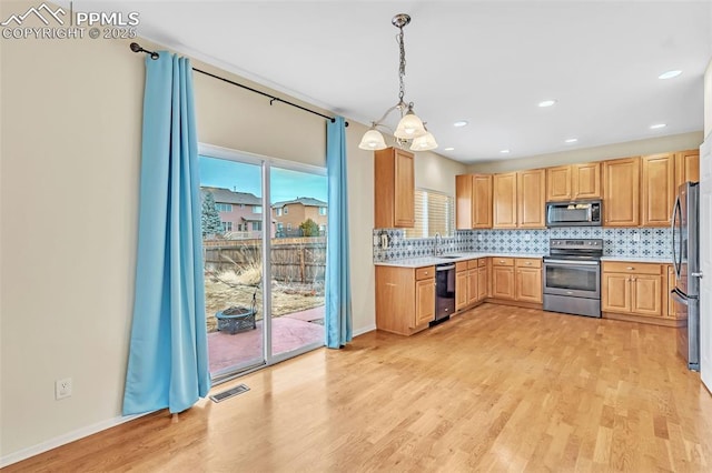 kitchen featuring appliances with stainless steel finishes, light wood-style floors, visible vents, and tasteful backsplash