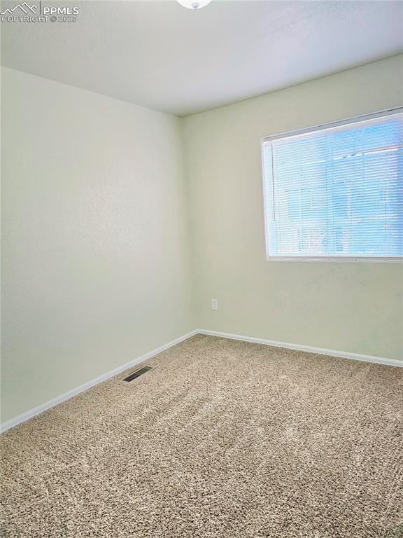 carpeted spare room with visible vents and baseboards