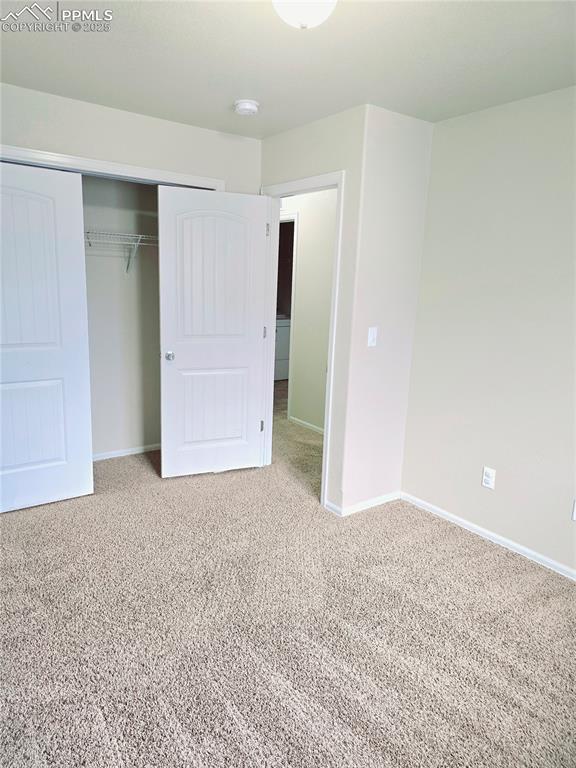 unfurnished bedroom with a closet, baseboards, and carpet