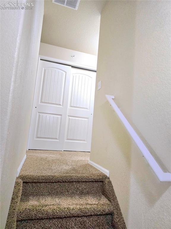 staircase featuring baseboards and visible vents