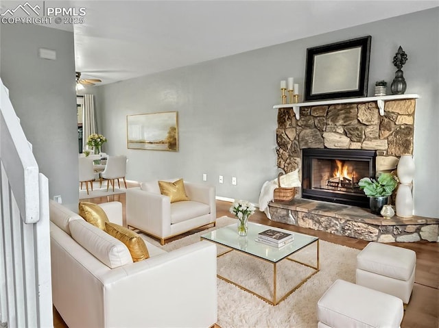 living room with a fireplace, wood finished floors, and a ceiling fan