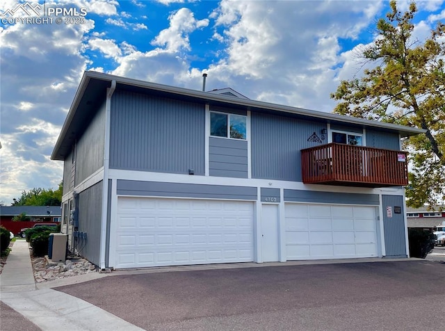 view of front of home with an attached garage, a balcony, and aphalt driveway