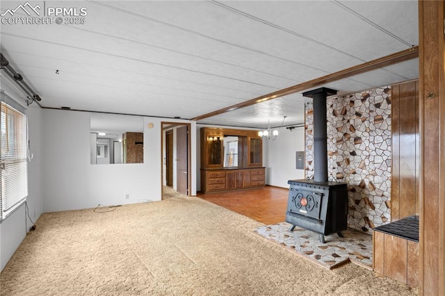 unfurnished living room with a wood stove, electric panel, and carpet floors