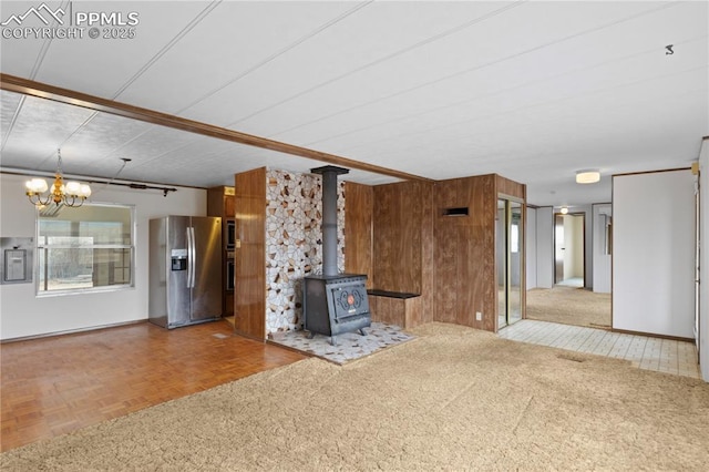 unfurnished living room with a wood stove, electric panel, and wooden walls