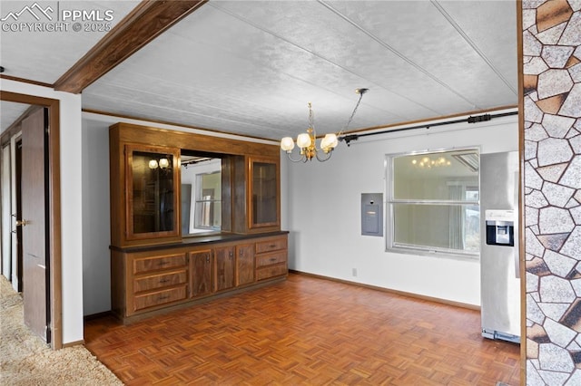 interior space featuring baseboards, electric panel, and a notable chandelier