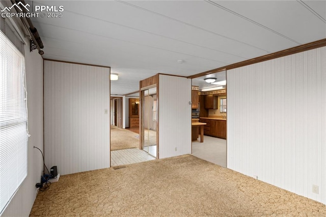 empty room featuring ornamental molding and light colored carpet