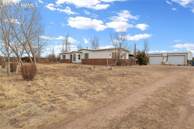 view of yard with driveway, an attached garage, and an outbuilding