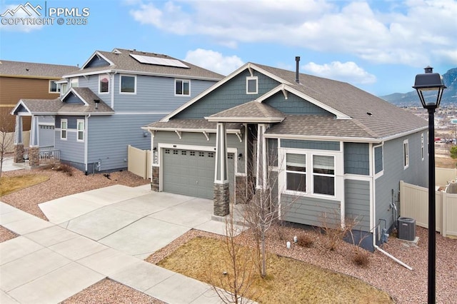 view of front of home with concrete driveway, roof with shingles, an attached garage, fence, and cooling unit