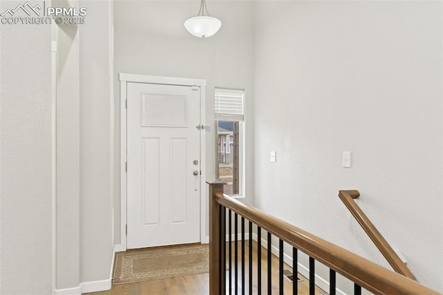 hallway with an upstairs landing, baseboards, and wood finished floors