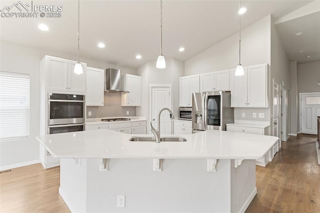 kitchen with stainless steel appliances, a spacious island, a kitchen bar, a sink, and wall chimney exhaust hood