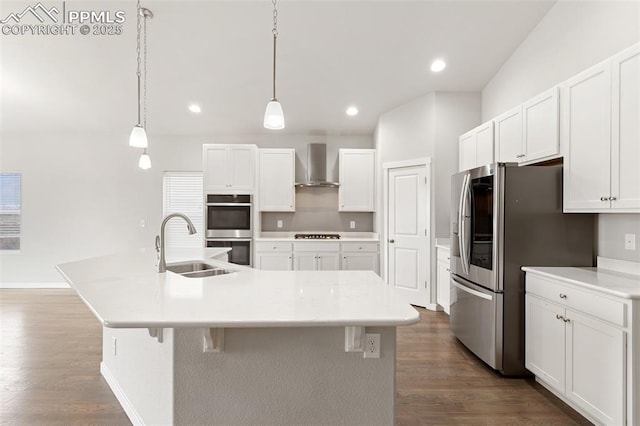 kitchen featuring a sink, white cabinetry, appliances with stainless steel finishes, a large island, and wall chimney exhaust hood