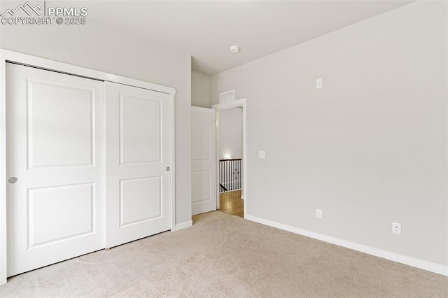 unfurnished bedroom with baseboards, a closet, visible vents, and light colored carpet