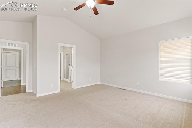 empty room featuring light carpet, baseboards, visible vents, and vaulted ceiling